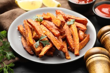 Delicious sweet potato fries with spices and sauces on table, closeup