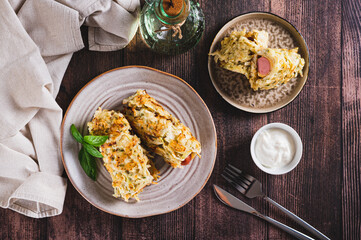 Sausages wrapped in shredded cabbage pancakes on a plate on a table top view