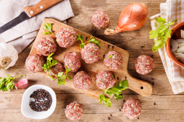 raw meatballs on wooden board with herbs