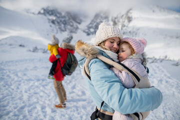 Obraz premium Young family is enjoying winter holiday in the mountains, standing in the middle of snowy landscape.