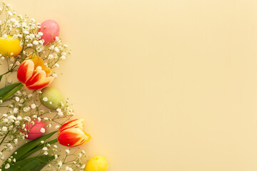 Spring Easter background, multi-colored Easter eggs with tulips and gypsophila on a yellow background