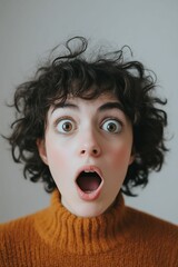 Woman with curly hair in brown sweater, shocked.