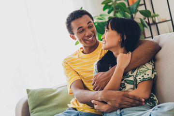Photo of cheerful adorable sweet couple wear t-shirts sit couch vacation together romantic time indoors living room