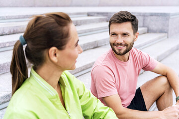 Couple Enjoying a Friendly Conversation While Sitting on Outdoor Steps During a Sunny Afternoon