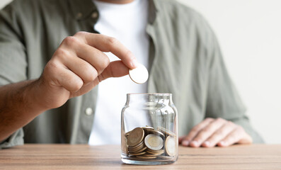 Hand Putting Coin in a Jar Full of Coins, Saving Concept