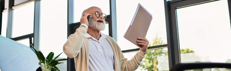 A well-dressed senior businessman speaks on the phone while reviewing important documents in a sleek office.