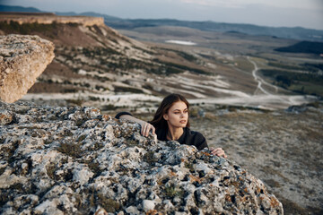 Serene woman perched on mountain peak overlooking majestic valley landscape