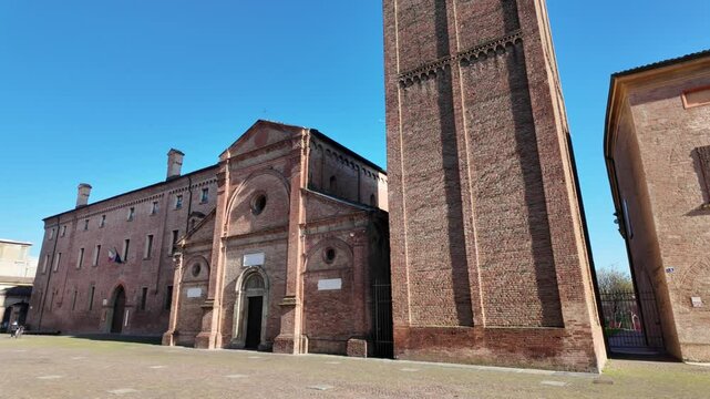 Pieve di Santa Maria in castello church tower rising majestically against a vibrant blue sky in Carpi, Italy, showcasing its intricate brickwork and architectural grandeur on a sunny day