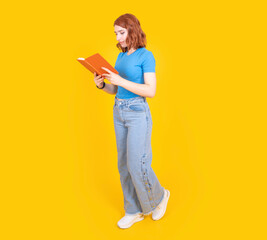 Reading book, full body side view young caucasian woman wear casual jean and t shirt walking and reading book isolated on yellow studio background. Education concept idea image. Copy space.