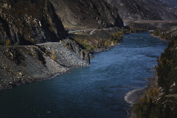 A view of the Katun River flowing coldly among the stones in the Altai Mountains, with a stark, rugged atmosphere.