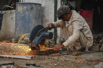 Poor old Welder cutting rods in his street workshop with electric cutter