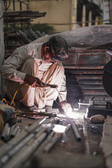 Welder welding metal with flash and sparks in his workshop