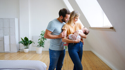 Loving Parents Holding Newborn Baby Son At Home In Loft Apartment