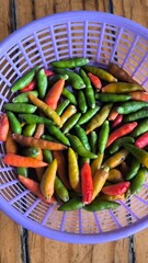 Chili peppers in a purple basket on a wooden table