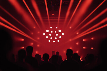 Silhouettes of people in a dark room illuminated by red lights and beams creating an energetic concert or club atmosphere
