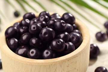 Ripe acai berries in bowl on table, closeup