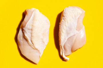 Uncooked raw chicken breast fillets on yellow background.