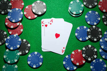 Poker chips and playing cards on green table, flat lay