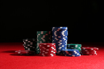 Poker game. Casino chips on red table against dark background