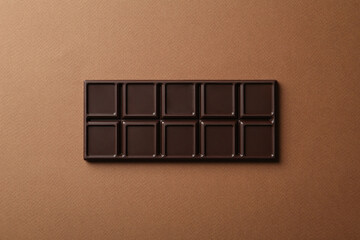 Tasty chocolate bar on brown background, top view