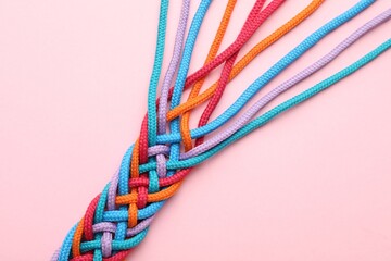Braided colorful ropes on pink background, top view. Unity concept