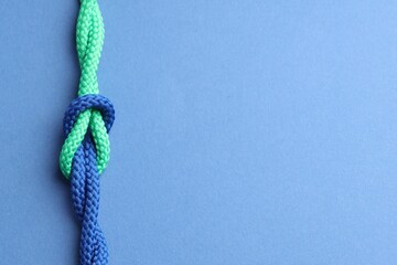Colorful ropes tied in knot on blue background, top view and space for text. Unity concept © New Africa