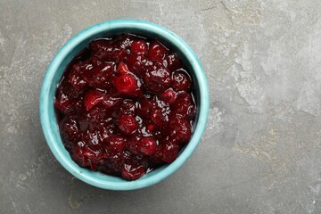 Tasty cranberry sauce in bowl on grey table, top view. Space for text