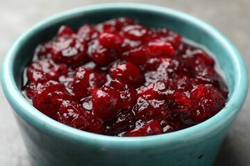 Tasty cranberry sauce in bowl on table, closeup
