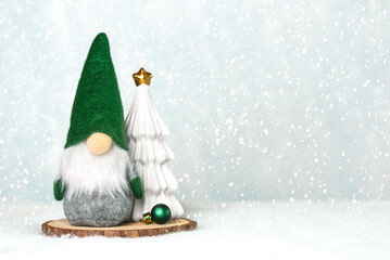 Christmas gnome with a christmas tree on a wooden base and snowflakes with space for text....