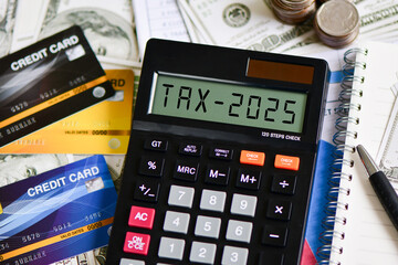 Tax 2025. Word Tax 2025 on calculator. Business and tax concept. Calculator, currency, dollar bills close up. Income Statement. paying the tax rate. Taxation, investment,