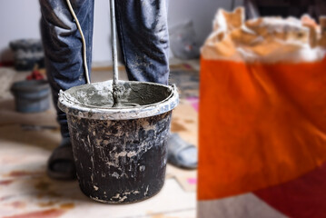 Mixing glue with mixer drill at the construction site.