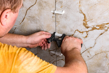 Installing leveling system tiles using black tongs.