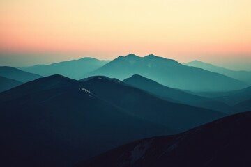 Fototapeta premium Breathtaking mountain view at sunrise. Misty peaks silhouetted against vibrant sky colors.