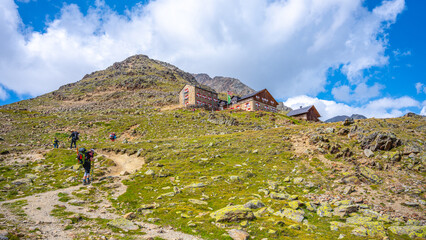 Hikers make their way toward Breslauer Hut, nestled in the Otztal Alps of Austria. Surrounding...