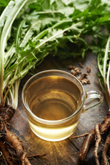 Herbal tea in a glass cup with fresh dandelion roots and leaves © Madeleine Steinbach
