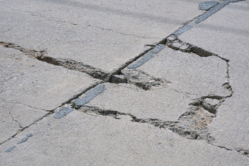 Cracks and broken texture with collapse of the old badly damaged concrete street surface