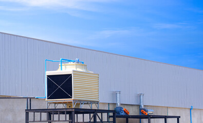 Square cooling tower outside of factory building against blue sky background, perspective side view with copy space