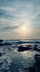 Obraz premium High tide on the rocky shore of the island against the backdrop of a beautiful sunset in a cloudy sky