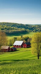Obraz premium A breathtaking view of rolling green hills and charming red barns under a clear blue sky in the countryside