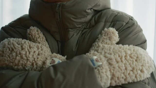 A man in a winter jacket and warm gloves is freezing from the cold.
A man in a very cold winter.
It's frosty outside and a man is trying to warm up.
A man in winter gloves.
Fluffy gloves on hands