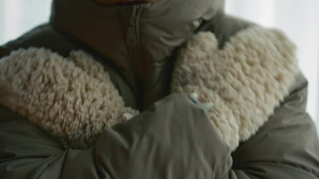 A man is freezing from the cold wearing winter fluffy gloves.
A man warms himself with warm gloves in cold weather.
The guy has winter gloves on his hands.
Gloves, winter, weather, snow