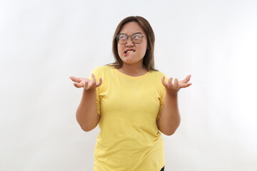 Irritated Asian woman with dark hair bites lips and gestures angrily being annoyed with someone expresses negative emotions wears t-shirt isolated over white background. People aggression anger.