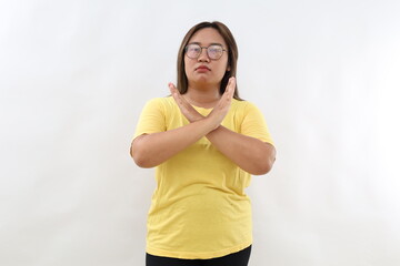 Confident serious Asian woman crosses hands makes stop forbid sign rejects something and says no wears casual t-shirt isolated white background says no has determined face expression.