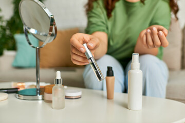 A plus-size woman explores her beauty routine surrounded by various cosmetics in her living room.