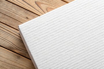 Naklejka premium Close Up of White Cardboard with Striped Texture on a Wooden Surface