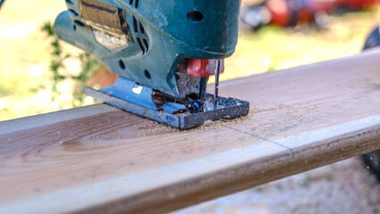 A close-up view of a jigsaw machine cutting timber in a garden