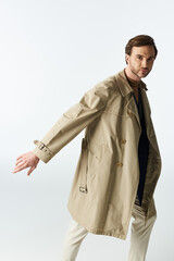 Stylish dandy in a trench coat striking a pose against a minimalist backdrop