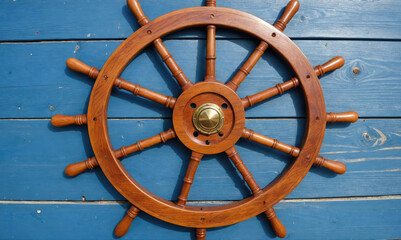 A wooden ship's wheel rests against a blue wooden wall