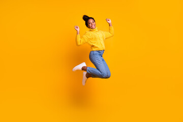 Fototapeta premium Carefree woman jumping against orange bright background