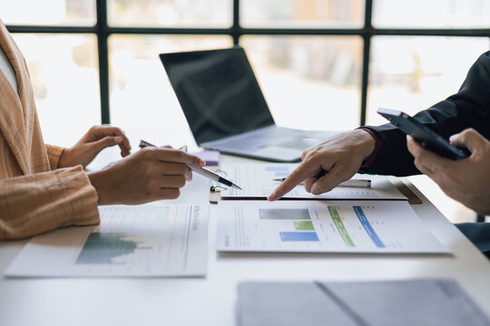 Meeting with a financial advisor and auditor are analyzing the financial figures in the business report. Investors are discussing cost analysis and reducing costs to increase profitability.
